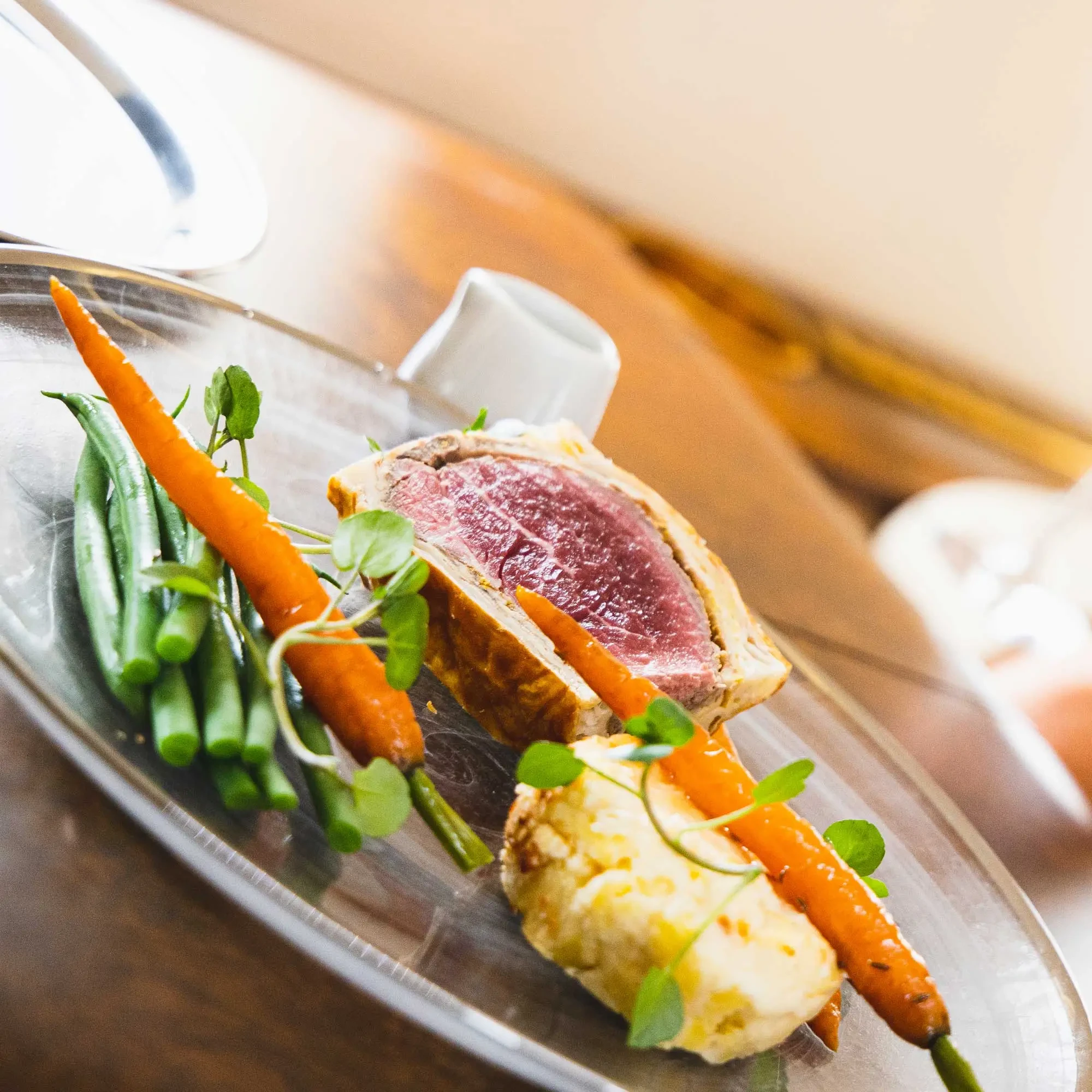 Close up some gourmet food which includes a fig, carrots and asparagus on a transparent plate.