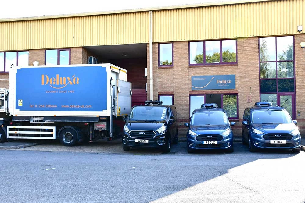 Outside the front of deluxe headquarters with lorry and cars in front.