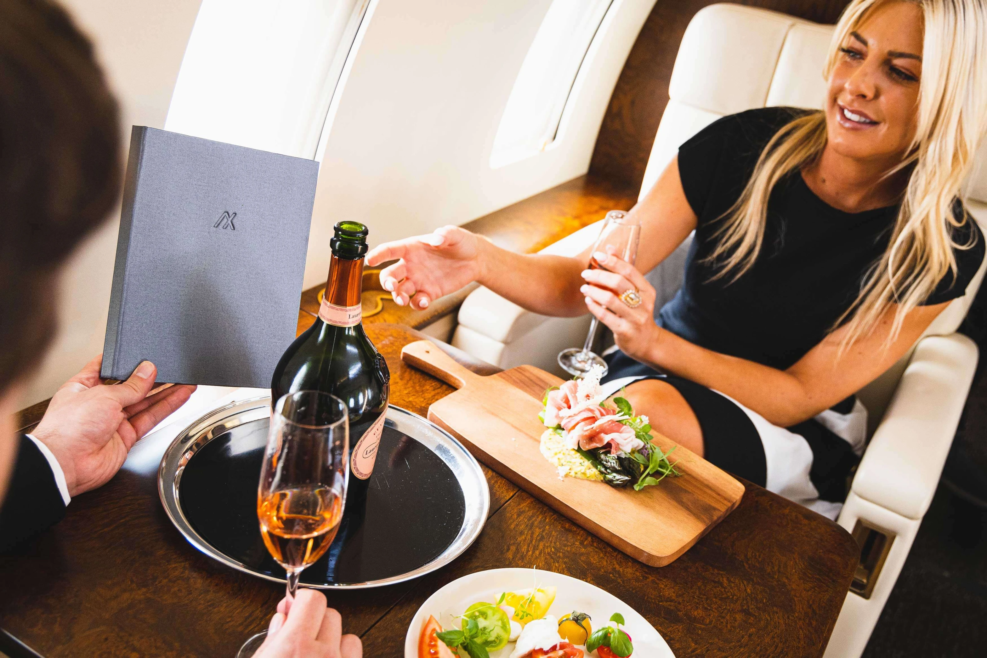 Man and women on a flight enjoying champagne and eating food.